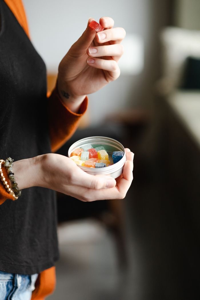 collection-02 Person holding colorful candies in a tin can with blurred background.